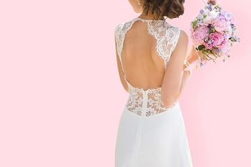 Frau trägt ihr gereinigtes Hochzeitskleid und hat einen Blumenstrauß in der Hand.